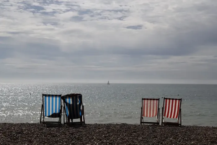 Framed Print : A woman sunbathes in a deckchair by the sea on a sunny day on Brighton Beach in southern