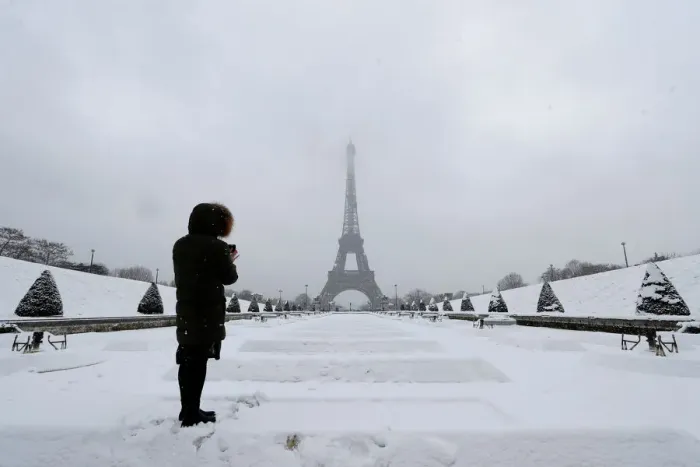 Framed Print : A woman takes pictures of the Eiffel Tower in Paris under the falling snow as winter Framed Print : A woman takes pictures of the Eiffel Tower in Paris under the falling snow as winter