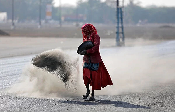 A woman throws a mixture of black ash, cement, concrete powder