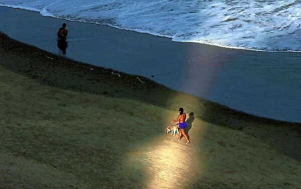 A woman walks with her dog on the Boa Viagem beach in Recife