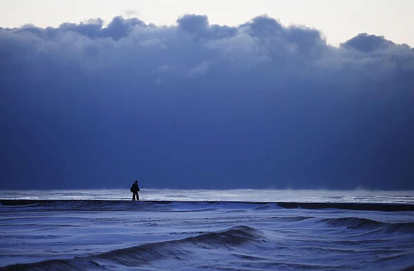 A woman walks along a frozen beach at Lake Michigan in Chicago
