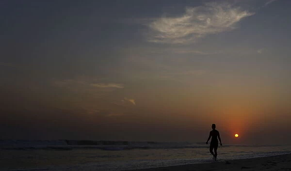A woman walks during sunset on Barra da Tijuca beach in Rio de Janeiro