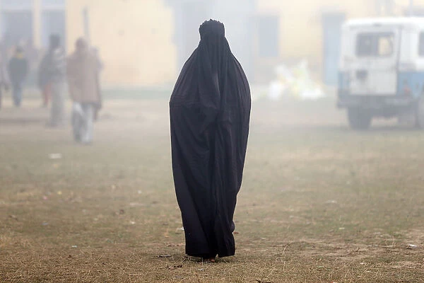 A woman wearing a burka leaves a polling booth after voting during the state assembly