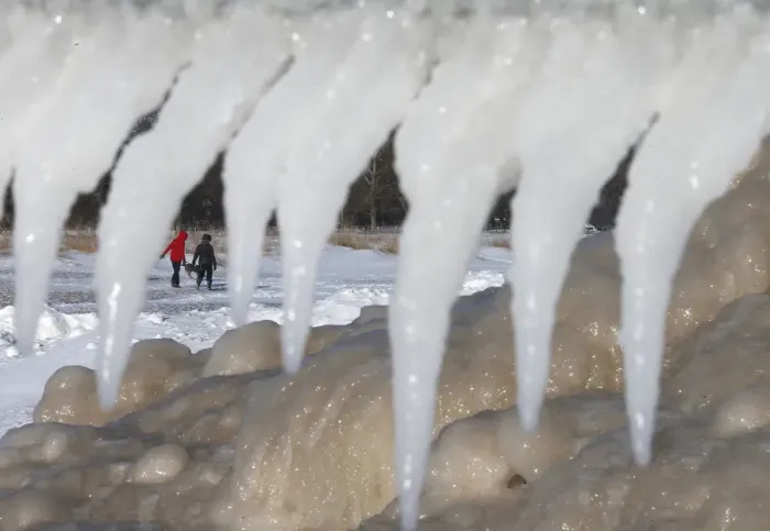 Framed Print : Two women are framed by icicles and mounds of frozen ice as they walk along a beach in Framed Print : Two women are framed by icicles and mounds of frozen ice as they walk along a beach in
