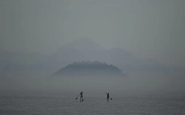 Two women paddle on stand up paddle boards at Copacabana beach in Rio de Janeiro