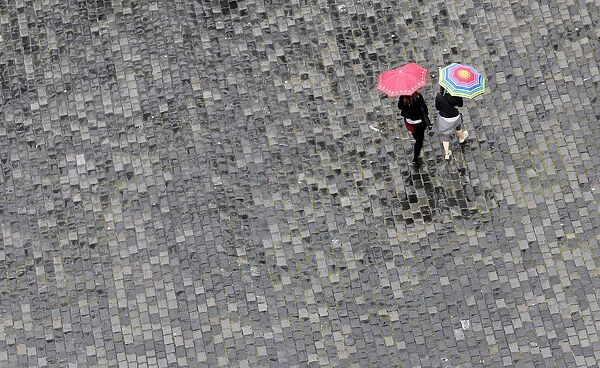 Women walk under umbrellas during a rainy day in Prague