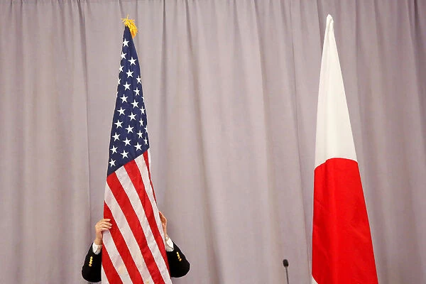 A worker adjusts the U. S. flag before Japanese Prime Minister Shinzo Abe addresses media
