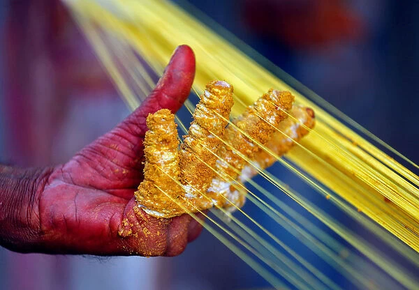 A worker applies colour to strings which will be used to fly kites