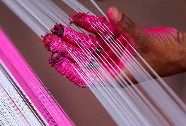 A worker applies colour to strings which will be used to make kites