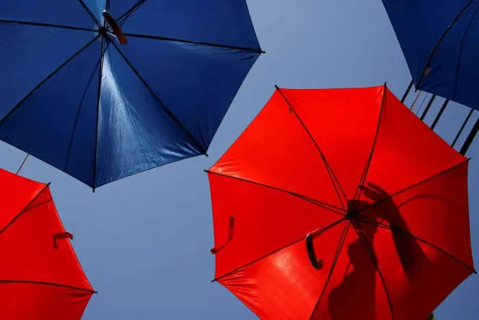 Framed Print : A worker arranges coloured umbrellas hanging over a street in preparation for a music Framed Print : A worker arranges coloured umbrellas hanging over a street in preparation for a music