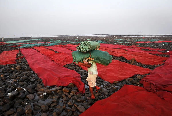A worker carries carpets used for wedding functions to be washed along the Arabian Sea in