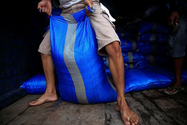 A worker drags a sack of industrial salt at a warehouse in Jakarta
