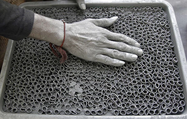 A worker fills gunpowder mixture in small paper rolls to make firecrackers at a factory