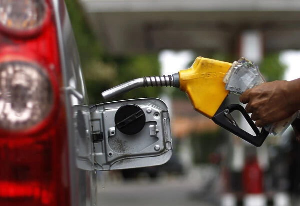 A worker fills a tank with subsidized fuel at a fuel station in Jakarta