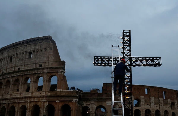 A worker lights up candles on a cross before the Via Crucis (Way of the Cross