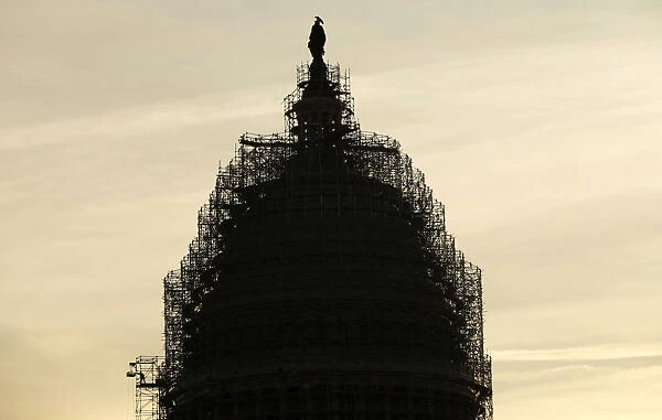 A worker reaches for supplies while working atop the scaffolded dome of the U. S