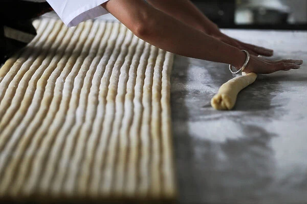 Worker rolls dough for rose pastries at a factory that makes flower pastries, in Kunming