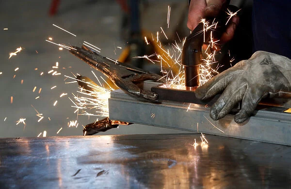 A worker welds a piece of metal at a steel workshop in Marseille
