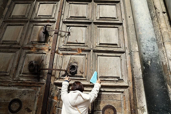 A worshipper touches the closed doors of the Church of the Holy Sepulchre in Jerusalem s