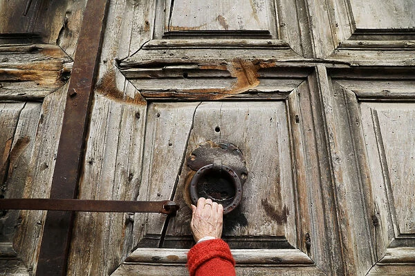 A worshipper touches the closed doors of the Church of the Holy Sepulchre in Jerusalem s