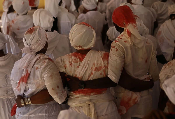 Worshippers with stains of goats blood on their clothes participate in a ceremony during