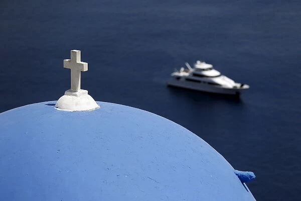 A yacht is seen below the village of Oia on the Greek island of Santorini