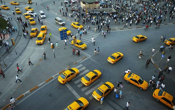 Yellow taxis pass people standing in silence during a protest at Taksim Square