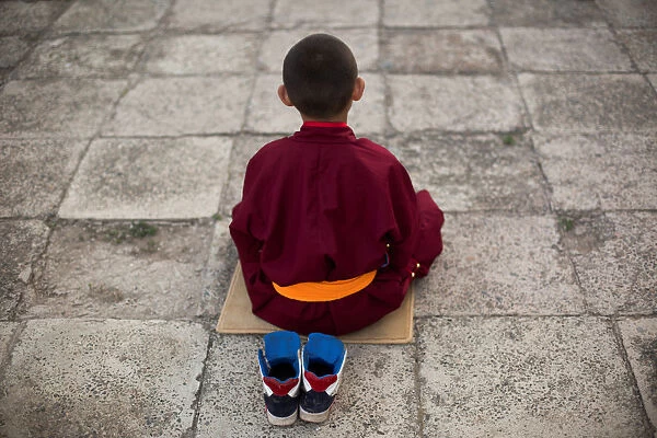 Young Buddhist monk Temuulen recites prayers in a courtyard at the Amarbayasgalant