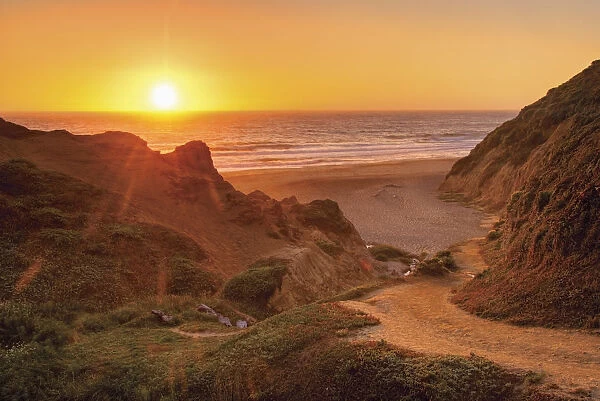 Orange california sunset on the ocean with trail down to a beach