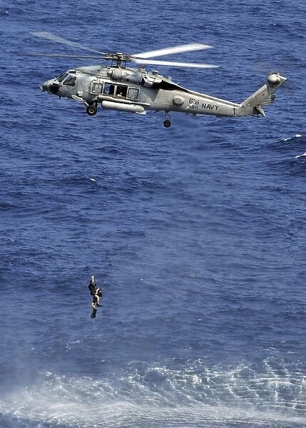 Search and rescue swimmers being hoisted into a helicopter