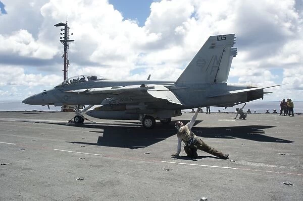 Shooters give the signal to launch an F  /  A-18E Super Hornet