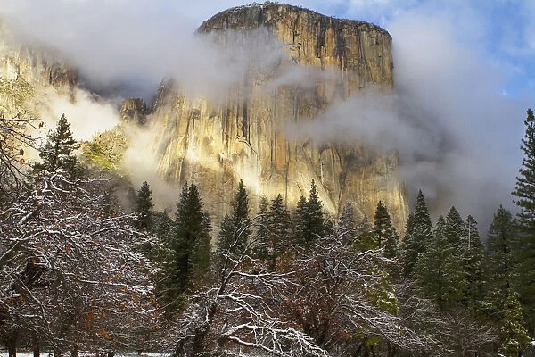 Yosemite national parks el capitan (el cap) peaks through winter storm clouds during a december storm; California, united states of america