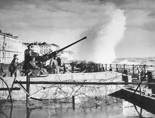 Sea spray breaks over a South Coast sea front wall on to an anti aircraft gun crew during