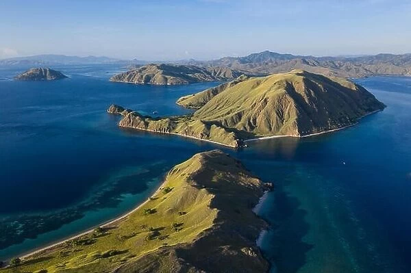 Seen from an aerial view, afternoon light shines on rugged islands in Komodo National Park, Indonesia. This area has high marine biodiversity