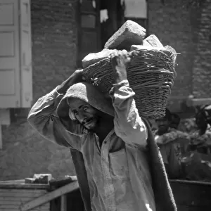 Kashmir - ragged man carries bricks in basket
