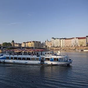 Sightseeing boat on Vltava River with East bank and Jiraskuv Bridge, Prague