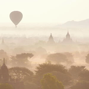 View over the temples of Bagan swathed in early morning mist, with hot air balloon drifting across the scene, from Shwesandaw Paya, Bagan, Myanmar (Burma), Southeast Asia