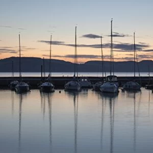 Yachts moored in The Cobb with Jurassic Coast and Golden Cap at sunrise, Lyme Regis