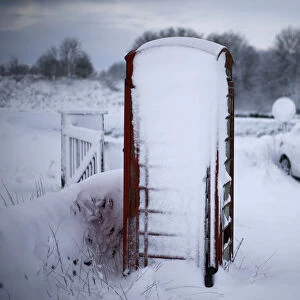 An abandoned car and a telephone box stand in snow near Ashbourne