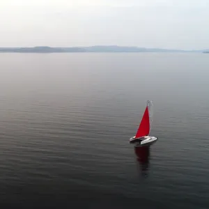 Aerial view shows a couple traveling on a sailing catamaran along the Yenisei River