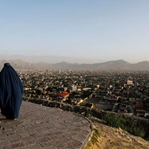 An Afghan woman walks on a hilltop overlooking Kabul, Afghanistan