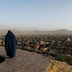 An Afghan woman walks on a hilltop overlooking Kabul, Afghanistan