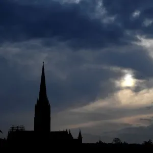 The afternoon sun pierces clouds behind Salisbury Cathedral
