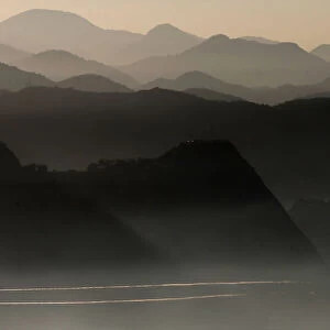 An airplane flies near mountains, as the sun rises in Rio de Janeiro