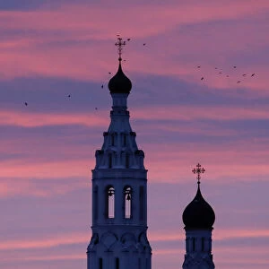 Birds fly over the Annunciation church at dawn in the village of Lipitsy
