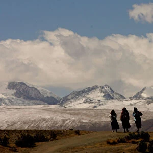 BOLIVIAN WOMEN AYMARAS WALK ON HIGHWAY BY ILLAMPU MOUNTAIN RANGE
