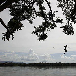 A boy jumps from a tree into Caura river in Maripa in the southern state of Bolivar
