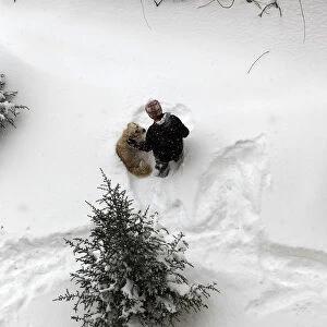 A boy plays with his dog in a snow-covered park in Ankara