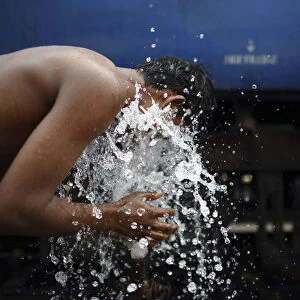 A boy washes using a pipe that supplies water for trains at Old Delhi railway station