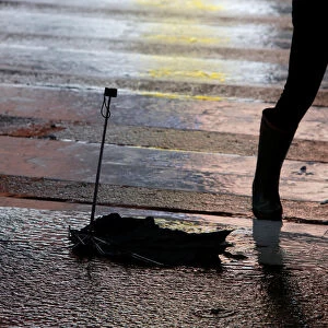 A broken umbrella is seen on the ground as a woman passes by it in Times Square during a